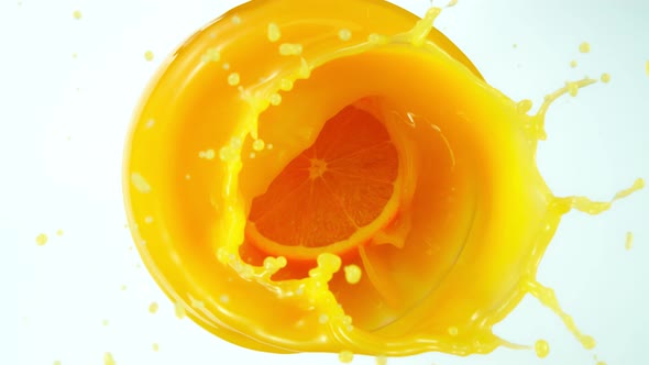 Super Slow Motion Shot of Orange Slice Splashing Into Orange Juice Isolated on White at 1000Fps