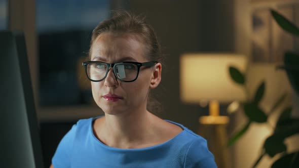 Woman Puts on Her Glasses and Continues to Work at the Computer at Night