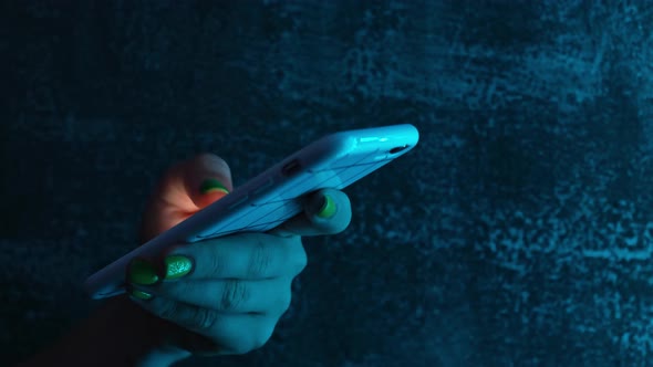 Woman Hands with Smart Phone Close Up in Trendy Neon Lights on Street