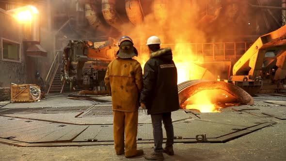Steelworkers standing near a blast furnace
