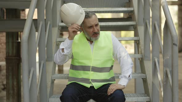 Depressed Adult Foreman Sitting Outdoors on Stairs