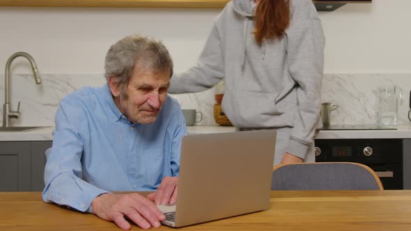 Happy Grandfather and Daughter Hugging Looking at Something on a Laptop at Home