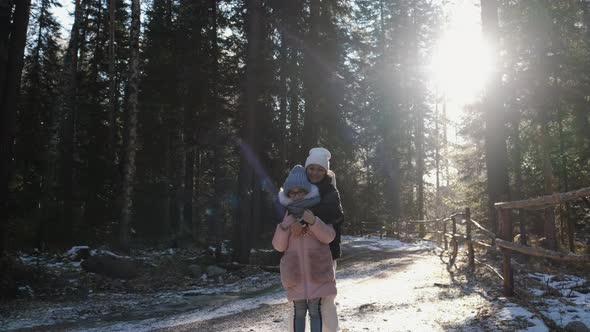 Young Woman and Teenager Girl Mom and Daughter Hug Look at the Camera and Smile in Nature Near the