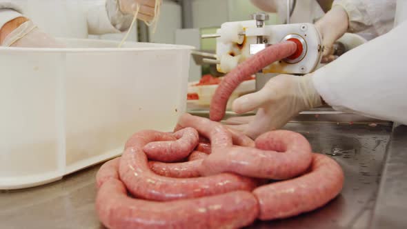Butchers making sausage from mincer