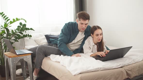 Beautiful Young Caucasian Couple Use Laptop Lying on Bed