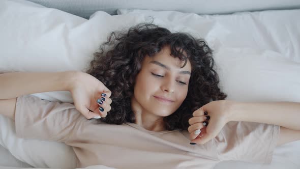 High Angle View of Cute Young Woman Sleeping Then Waking Up and Stretching Arms in Comfortable Bed