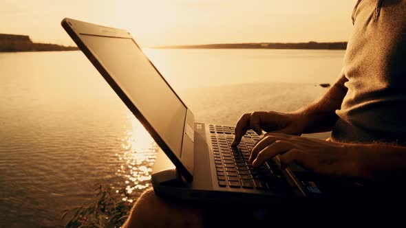 Man's Using Laptop Computer on Top of a Hill by the River