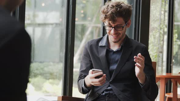 Overjoyed young businessman professional winner looking at smartphone screen, celebrate success read