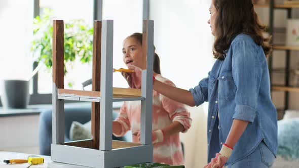 Mother and Daughter Painting Old Table at Home