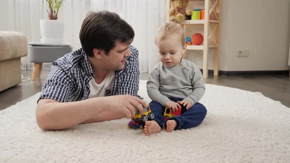 Father lying with his baby son on carpet and playing