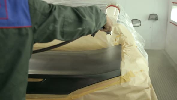 Close-up of a Car Mechanic Paints the Trunk of the Car Spraying Black Paint