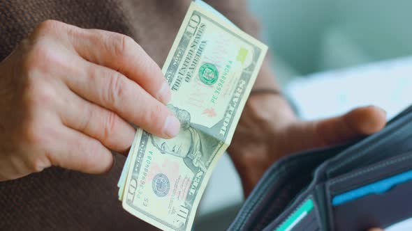 Close Up View of an Old Man's Hands Adding Dollar Bills to His Wallet