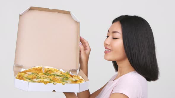 Asian Woman Opening Box And Smelling Pizza Over White Background