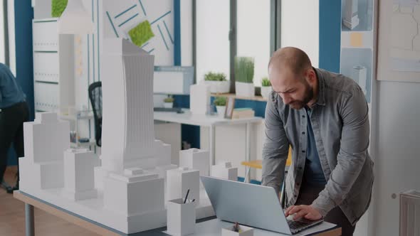 Man Holding Laptop to Work on Building Model Design and Blueprints Plan