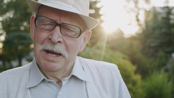 Happy Senior Man Emotionally Exhales, Rejoices and Tells Into the Camera in Park