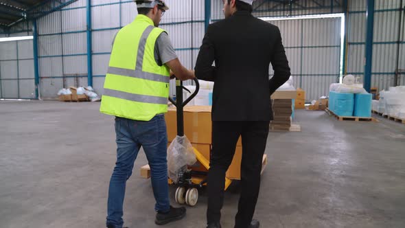 Factory Workers Deliver Boxes Package on a Pushing Trolley in the Warehouse