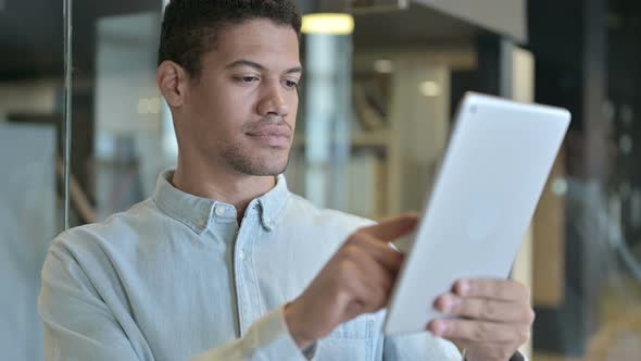 Young African Man Using Tablet in Modern Office