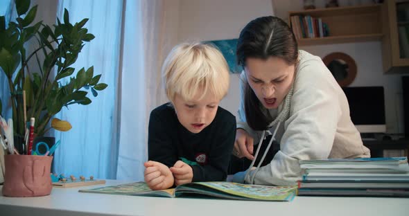 Young Mother with Preschool Child Boy Reading the Book with Labyrinths