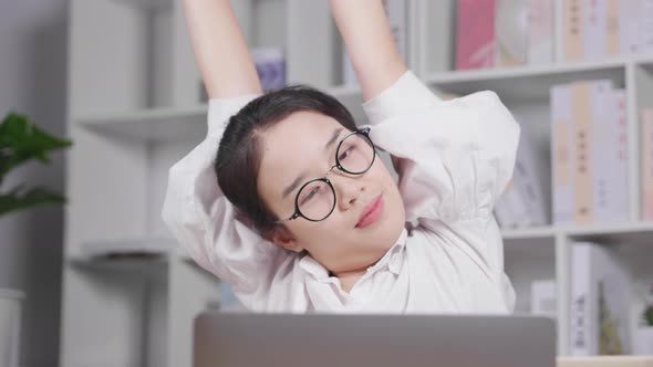 Asian young woman working on laptop and taking a rest, raising her hands up