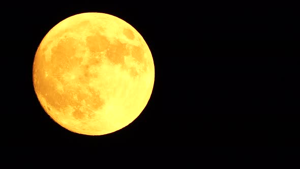 Glowing Yellow Huge Full Moon As Seen From Earth Through the Clouds Against Starry Night Sky