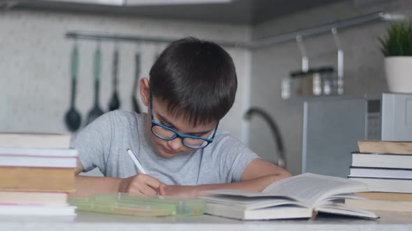 A Boy Does Homework Using Many Textbooks and Books. Camera Movement