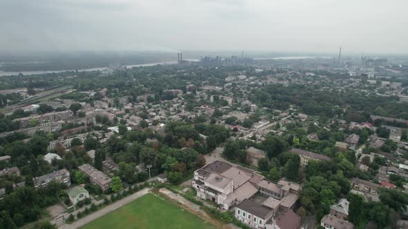 Aerial View of the City Near a Large Industrial Plant with Pipes and Smoke