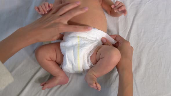 Mother Changing Diaper on Her Newborn Baby.