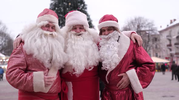 Portrait of Happy Senior Men in Costumes of Santa Claus on the Background of the Christmas Tree
