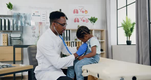 Male Doctor Checking Littel Girl's Heartbeat Using Stethoscope During Her Visit to Medical Center