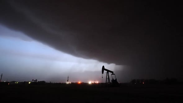 Silhouette of pumpjack in oil field as dangerous thunderstorm rolls in