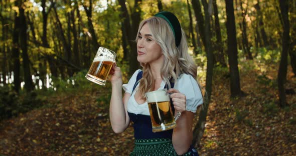 Slavic Woman Smiles and Has a Fun with Two Mugs of Beer in Autumn Forest