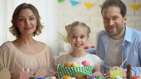 Friendly Family Posing at Camera With Basket of Brightly Colored Easter Eggs