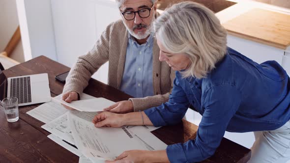 Slow motion shot of mature couple with papers and laptop on table