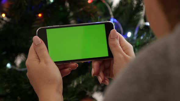 Female looks to green screen display phone  4K 2160p 30fps UltraHD footage - Woman holds greenscreen