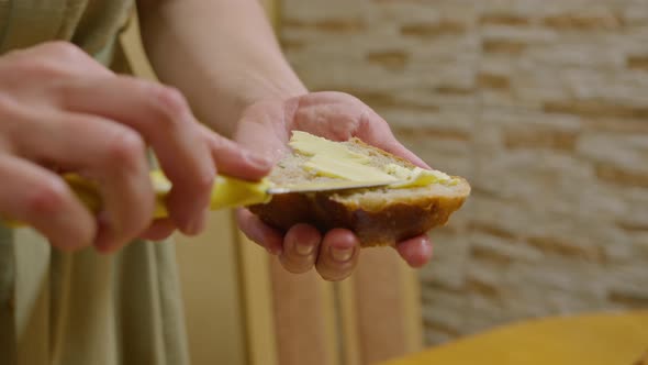 Commercial Footage a Young Girl Cuts Bread with a Knife Spreads a Sandwich with Butter and Pours