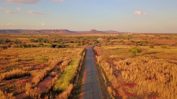 Beautiful cinematic aerial over a lone road passing through the barren dry fields of rural Bahia, Br