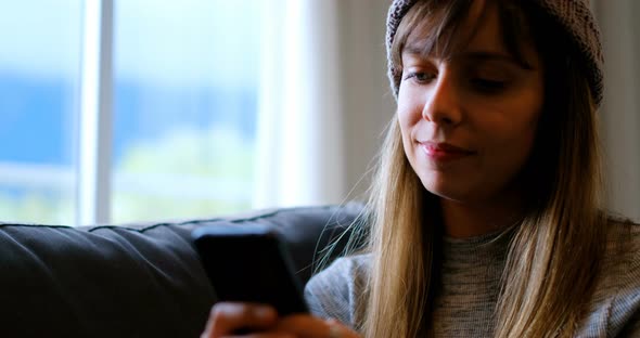 Woman using mobile phone on sofa 