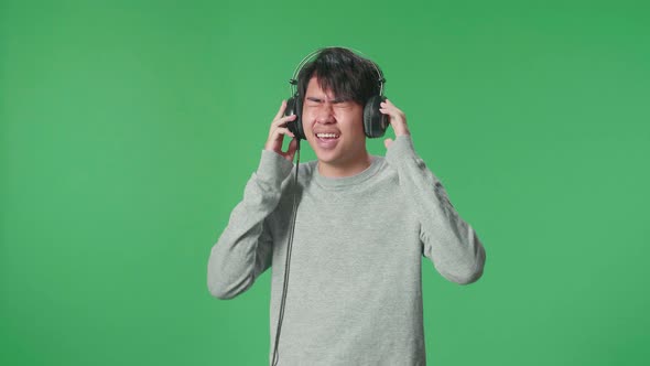 An Asian Man Listening To Music With Headphones And Dancing In The Green Screen Studio