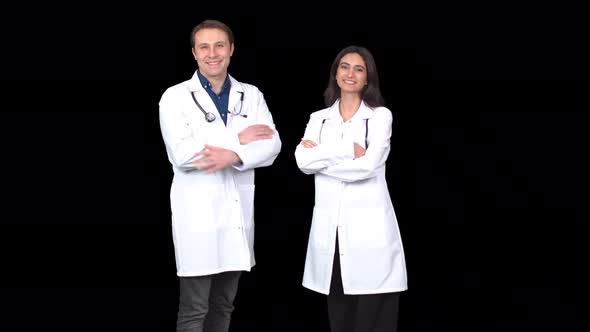 A male and a female doctor looking at the camera and laughing.