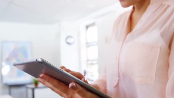 Smiling teacher using digital tablet in classroom