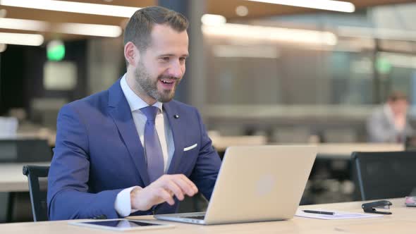 Successful Middle Aged Businessman Celebrating on Laptop at Work