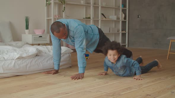 Carefree Dad and Son Exercising Push-ups at Home