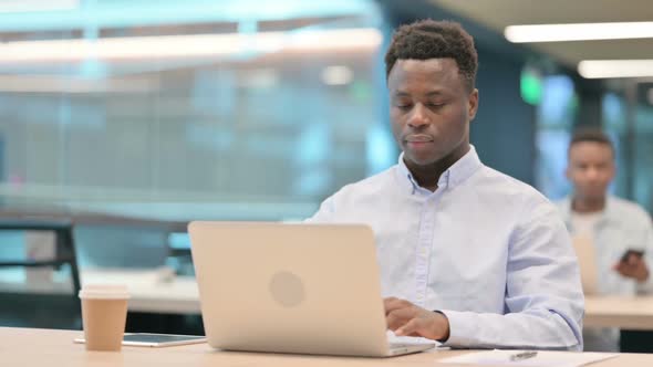 Thumbs Down By African Businessman with Laptop in Office