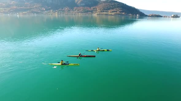 Three kayakers paddle in a scenic mountain lake.