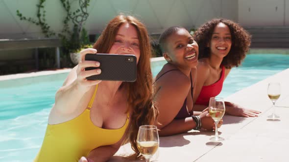 Diverse group of female friends having fun at pool taking selfie