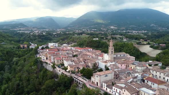 Aerial pan down forward approaching a small Italian town in a mountain landscape