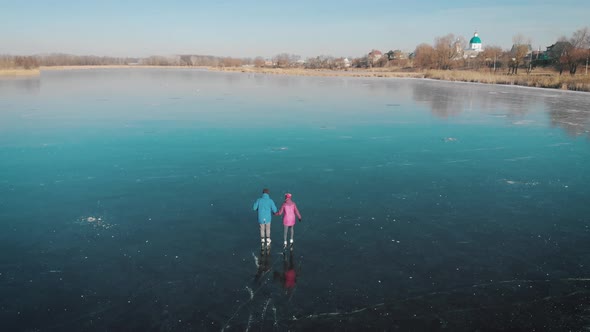 Aerial View Happy Couple Ice Skating Outdoors on a Frozen Lake on a Lovely Sunny Winter Day. Ice