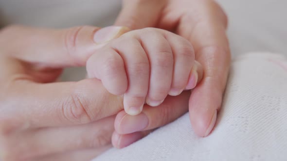 Parent Holding Newborns Hand in Slow Motion . Happy Family Mother and Her Newborn Baby Together