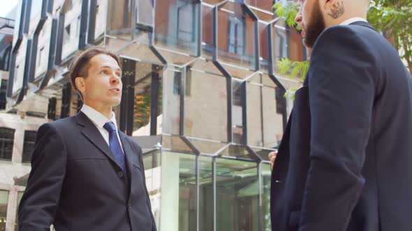 Confident businessman and his colleague in front of modern office building.