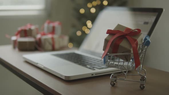 Gift Box In Cart With Blurred A Laptop On Desk At Home In Christmas Time